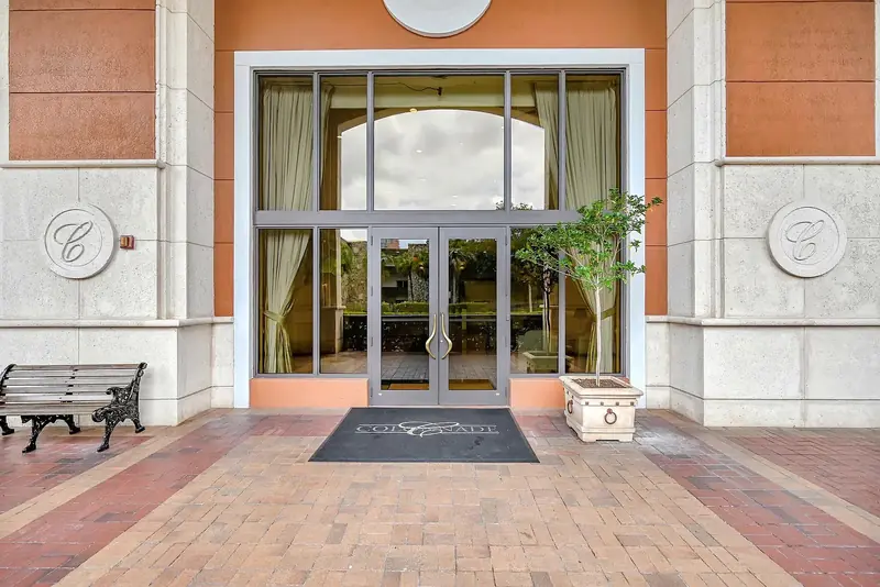Glass entrance doors at The Colonnade, with its monograms and branded mat.